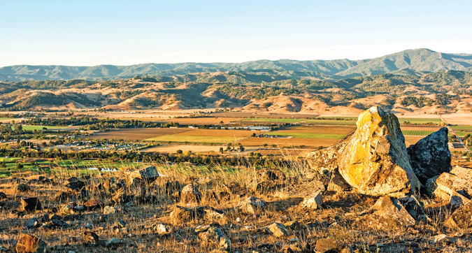 Rocks on ridge overlooking Coyote Valley with agricultural fields and mountains in distance