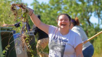 Volunteer holds up a plucked weed during a land steward event