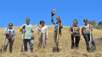 Volunteers pose for a photo on a golden hill at Furtado Barn