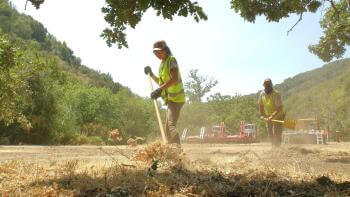 A volunteer tends to the land by raking up invasive grass