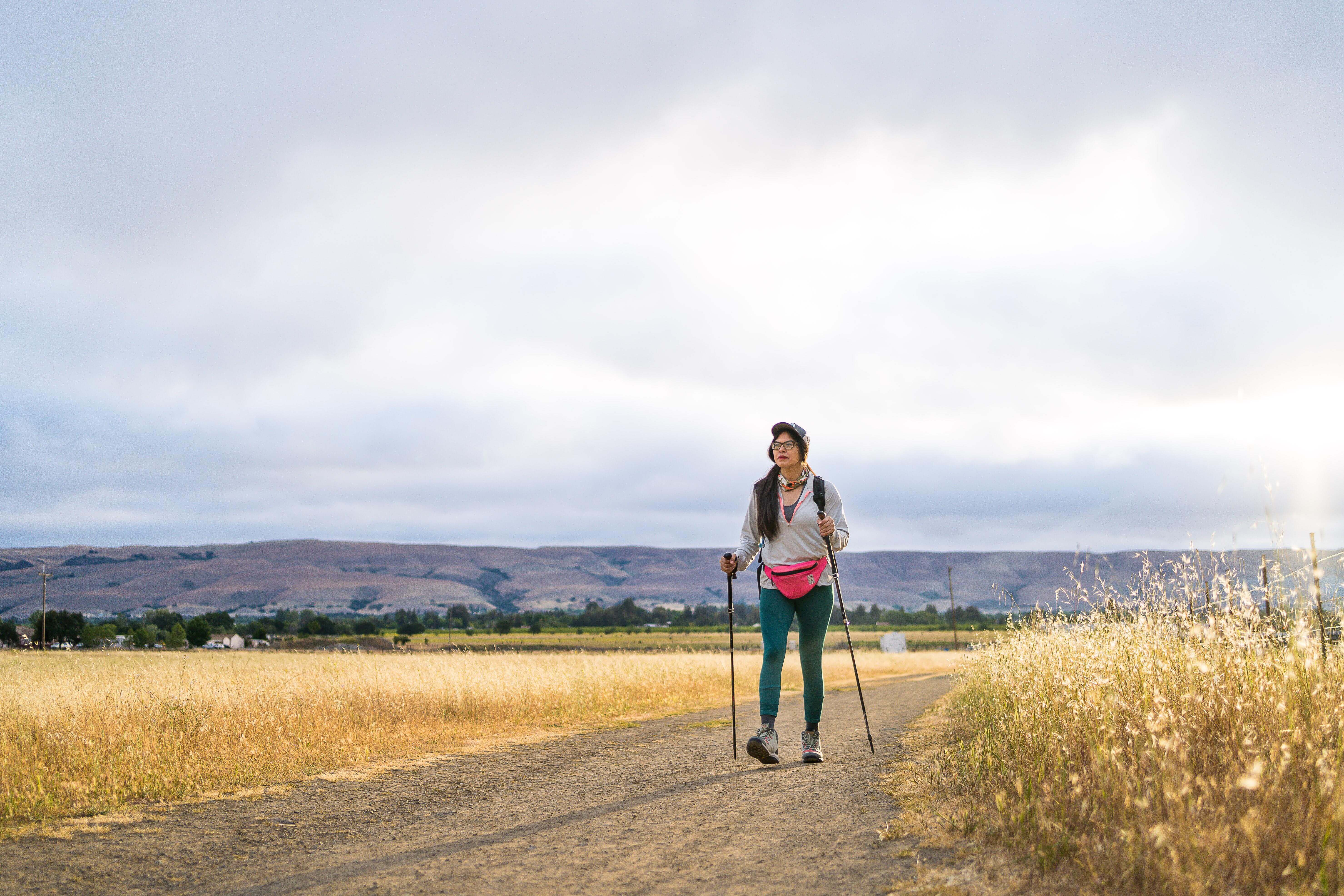 hiker with walking sticks on dirt trail