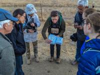 group of hikers surrounding and looking at a book